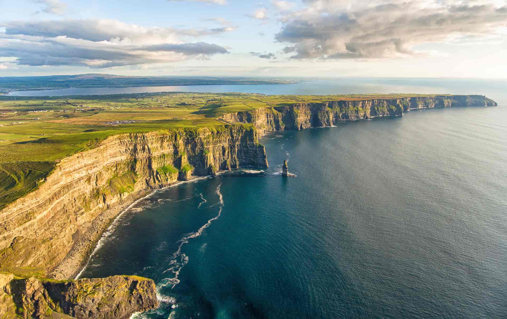 Cliffs of Moher dramatic sea cliffs meeting dark blue ocean water under cloudy sky
