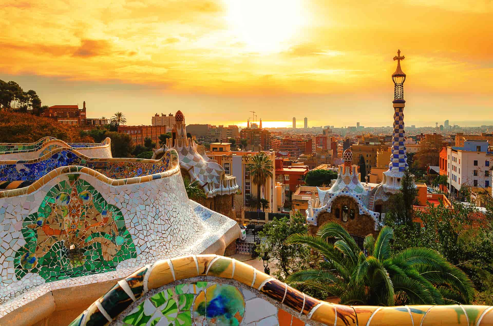 Mosaic serpentine bench overlooking Barcelona city skyline at sunset in Park Güell