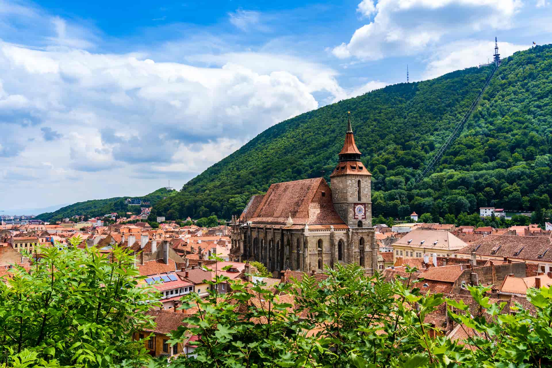 Black Church in Brasov overlooking terracotta roofs with Tâmpa Mountain in the background.