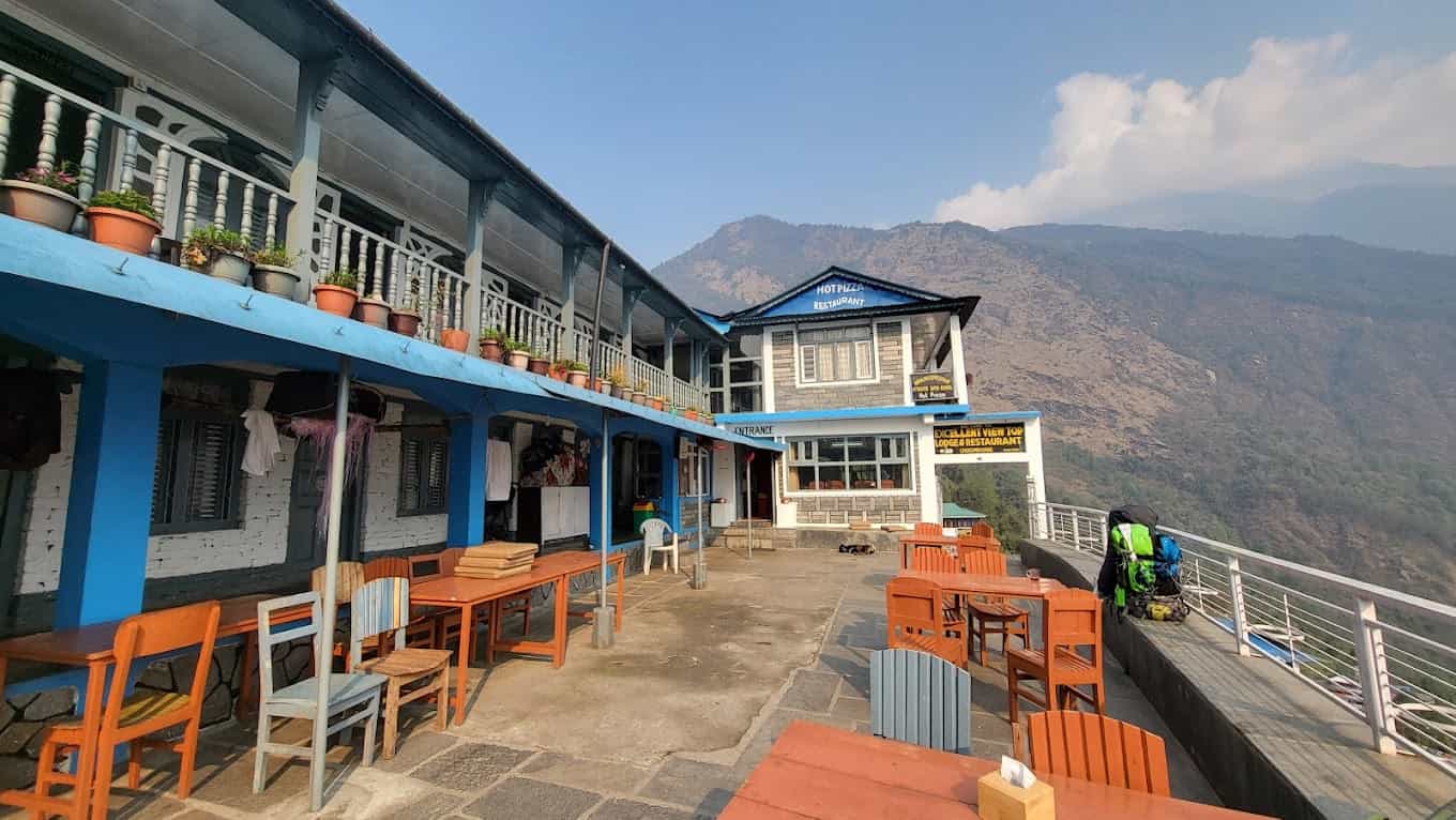 Lodge and restaurant patio with outdoor seating overlooking steep, arid mountains in Chhomrong.