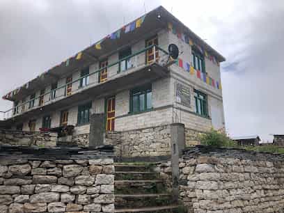 Zambala Hotel Samdo building with stone foundation, balconies, and prayer flags under cloudy sky.