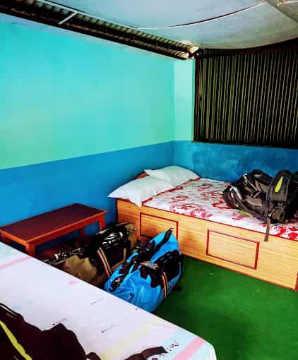 Hotel room with twin beds, luggage, and bright blue walls at Hotel Fulbari Lodge and Restaurant