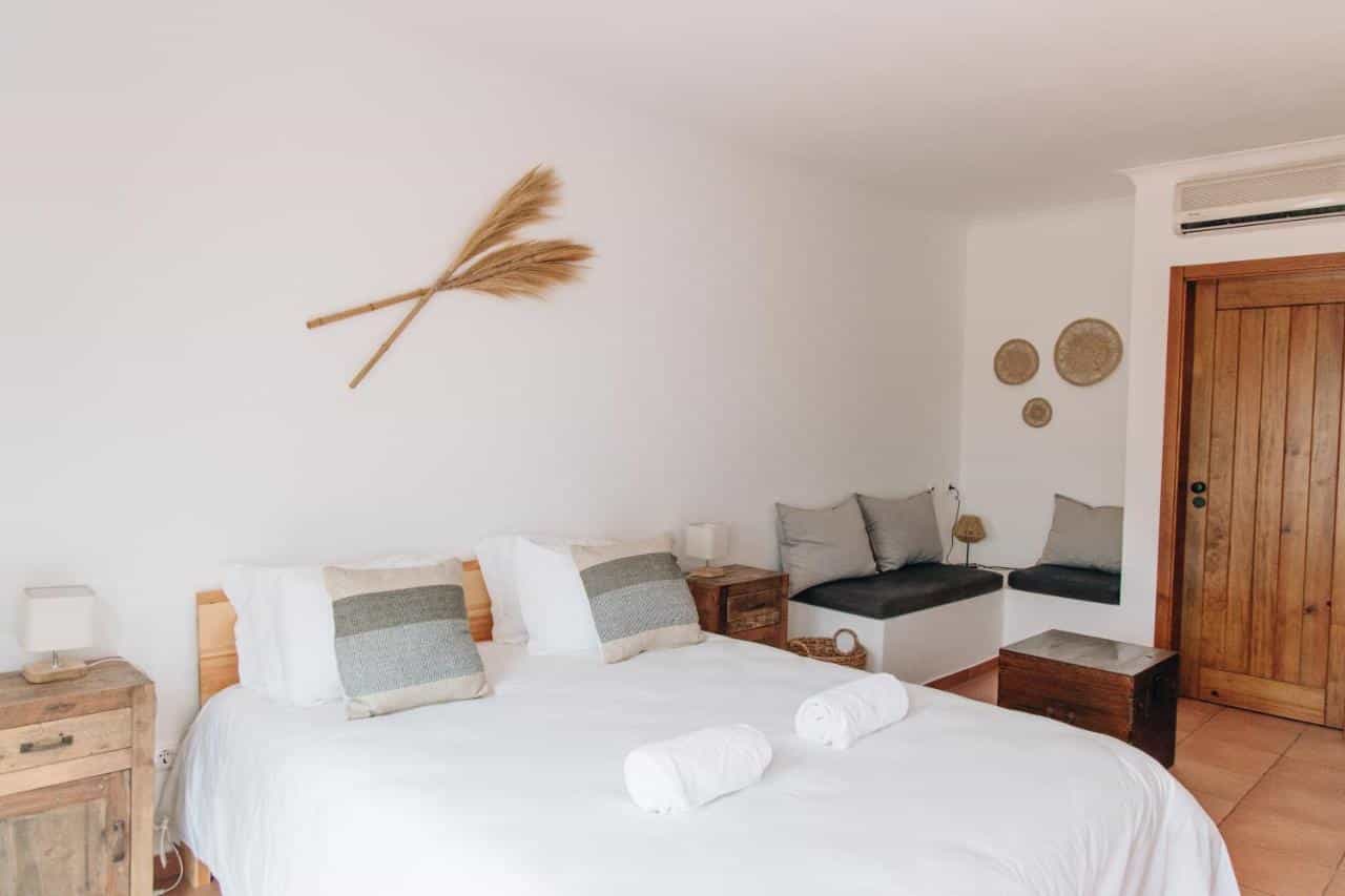 Bright bedroom with white walls, wooden bed, and natural fiber wall decor.