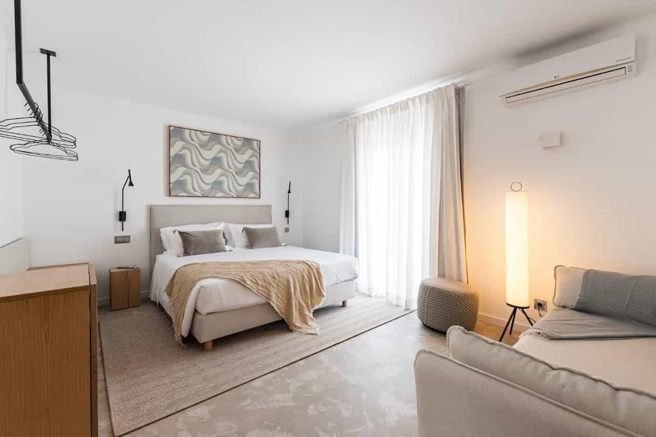 Bright modern hotel bedroom with king bed, abstract art, and sheer white curtains.