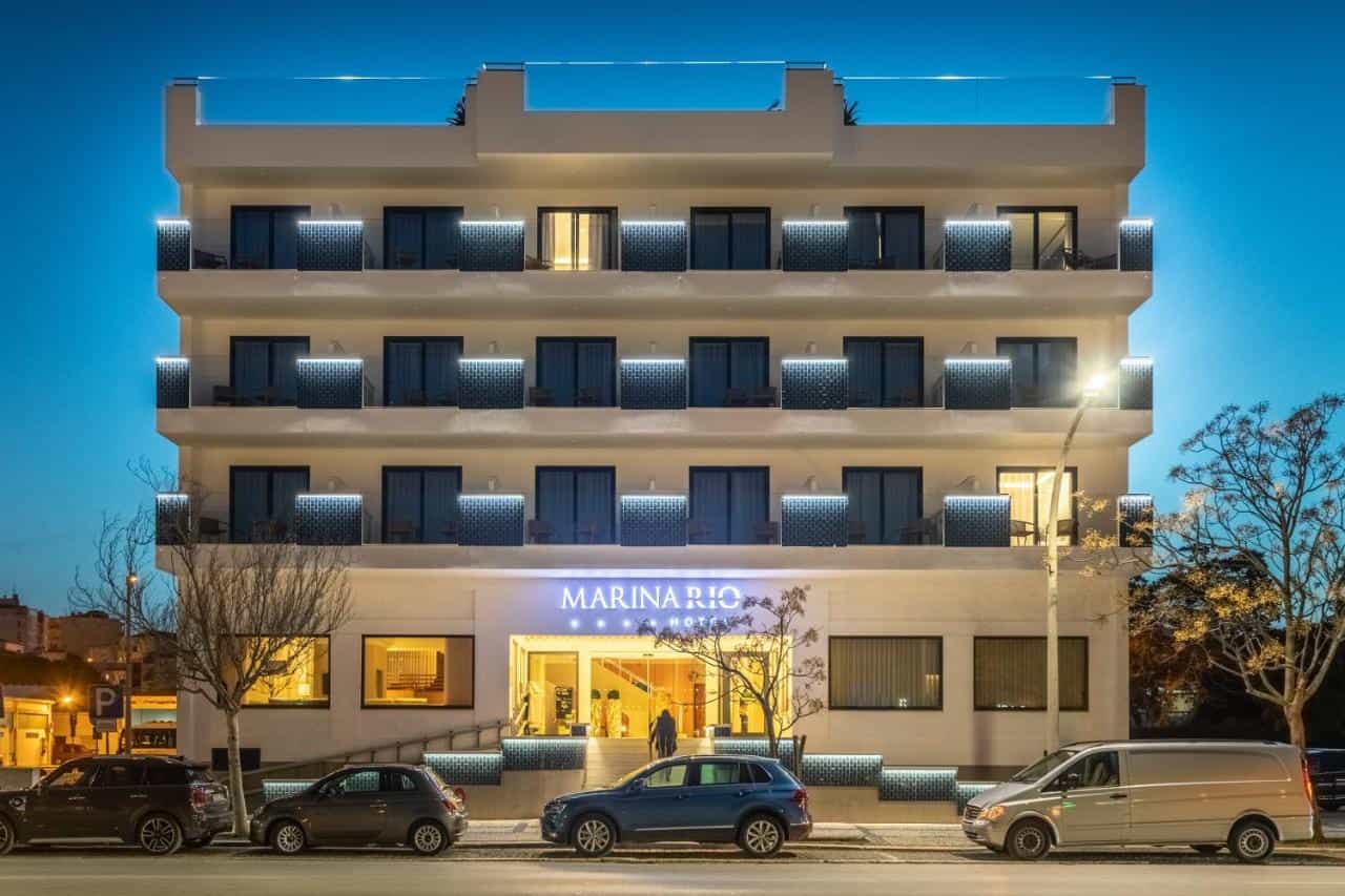 Marina Rio Hotel illuminated at dusk with cars parked along the street