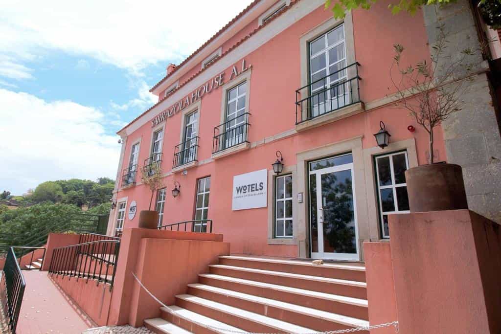 Sarrazola House A.L. building entrance with pink facade, white steps, and WOTELS sign.