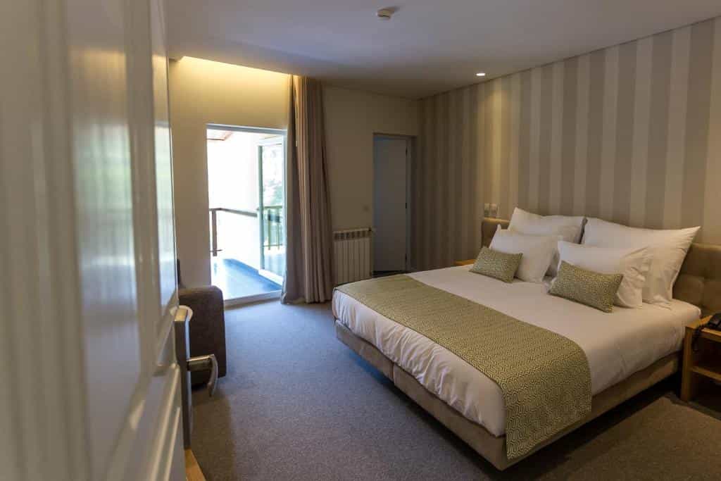 Hotel bedroom with large bed, striped wallpaper, and balcony access in Adelaide.
