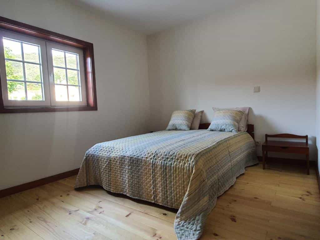 Bedroom interior with double bed, light wood floor, and window showing greenery outside, Paradela Inn