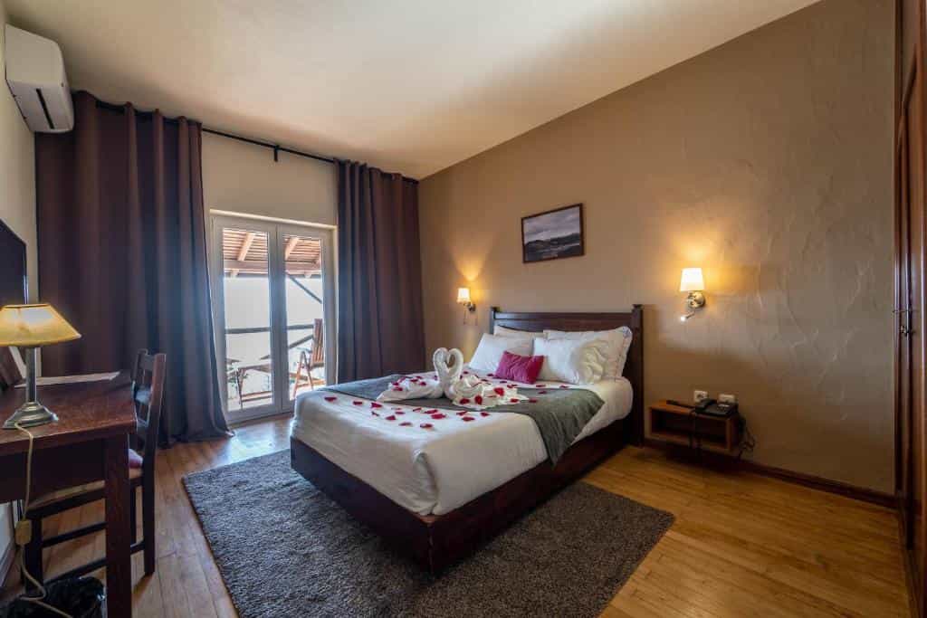 Hotel bedroom with swans made of towels and rose petals on the bed, view to balcony.
