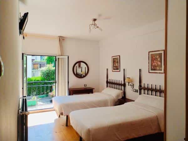 Twin bedroom with white linens, wooden headboards, and balcony access to greenery