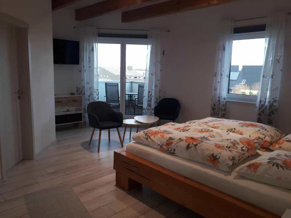 Bedroom with wooden bed, floral duvet, and balcony access in Eifelpension Radlertraum