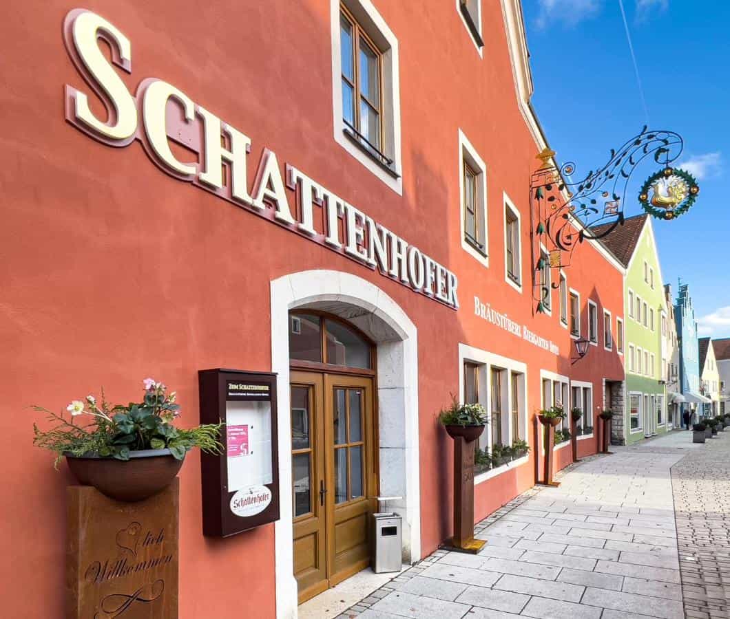 Schattenhofer Braugasthof building facade with large sign on cobblestone street with colorful buildings.
