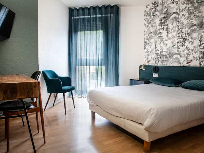 Hotel room with white bedding, wood floor, and jungle-print wallpaper near Grand Hôtel du Parc.