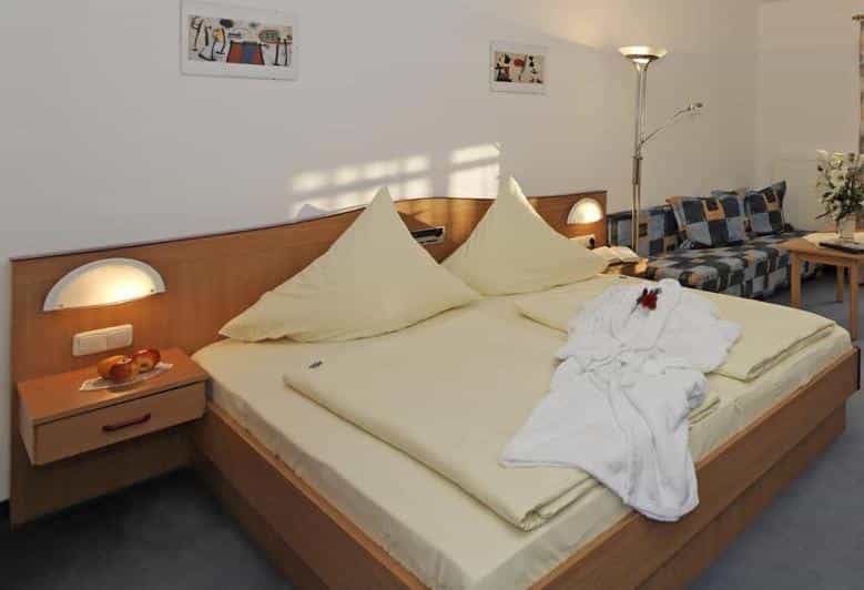 Double hotel room at Landhotel Tannenhof with white robe and apples on nightstand.