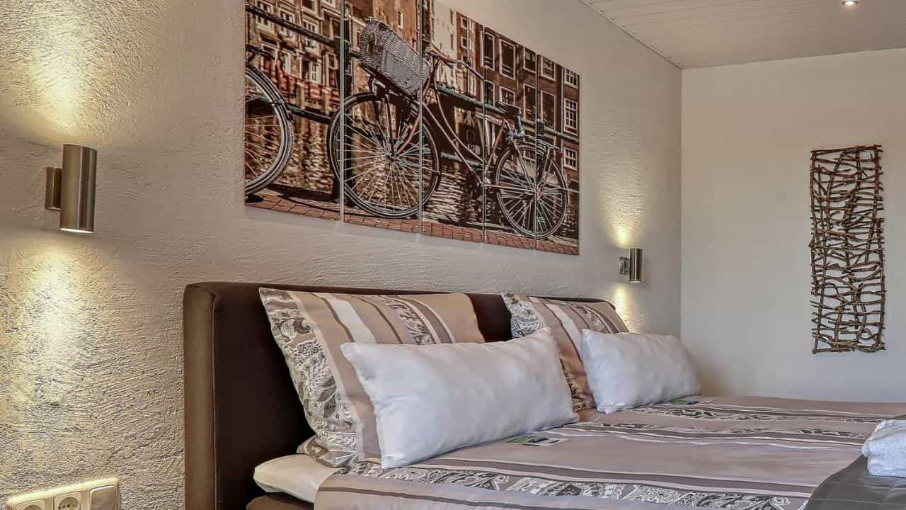 Bedroom with brown headboard, striped bedding, bicycle art, and wall sconces