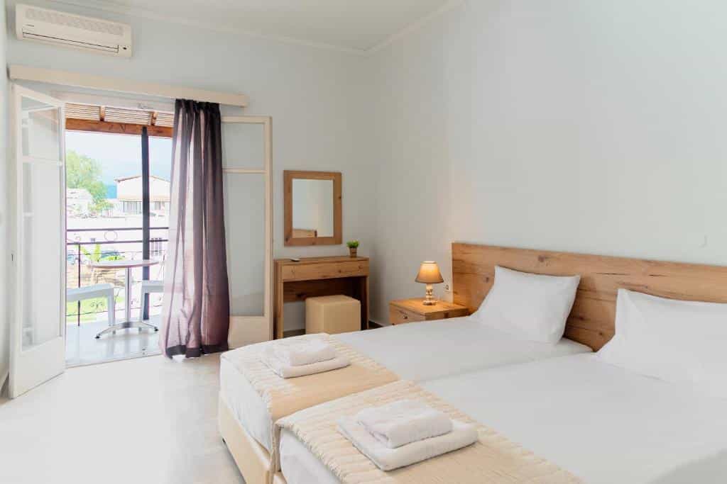 Twin beds with white linens, wooden headboard, balcony access, and air conditioning unit.