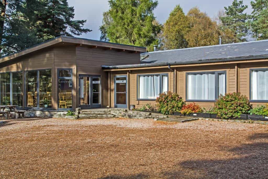 Old Pines Hotel and Restaurant building with wood siding surrounded by pine trees and wood chip ground cover.