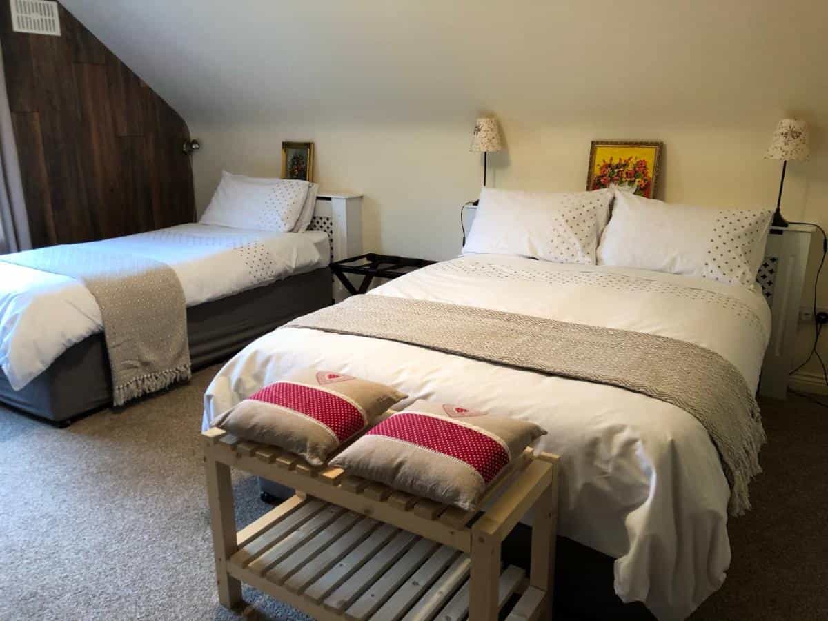 Bedroom with two beds, white linens, and slanted ceiling in Derrynane Bay House.