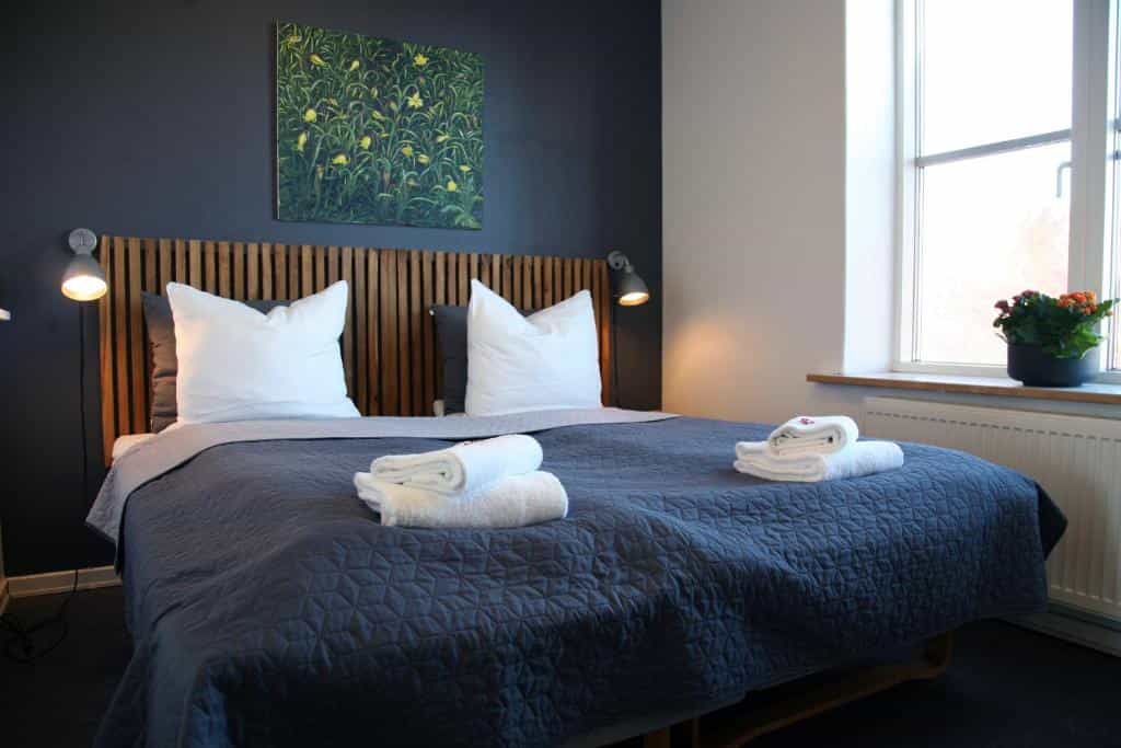 Bedroom in Nexø Modern Hostel with dark blue walls, wood headboard, and white linens.