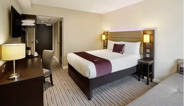 Premier Inn Glasgow Milngavie hotel bedroom with double bed, desk, and wall-mounted TV.