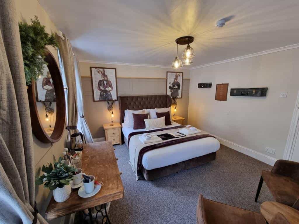 Cozy hotel bedroom with tufted headboard, rabbit artwork, and wooden console table.