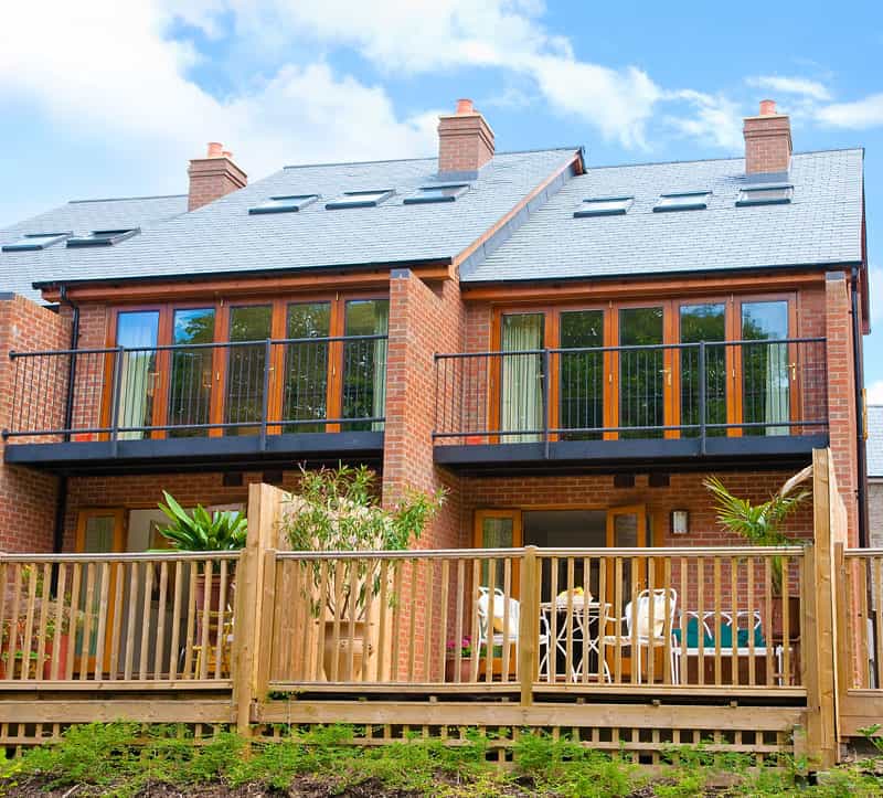 Brick holiday retreat with balconies and wooden deck under a blue sky