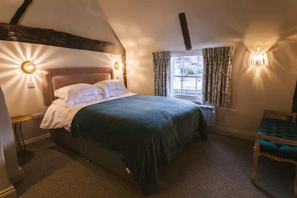 Cozy bedroom with exposed beams, plush bed, and starburst wall sconces near window