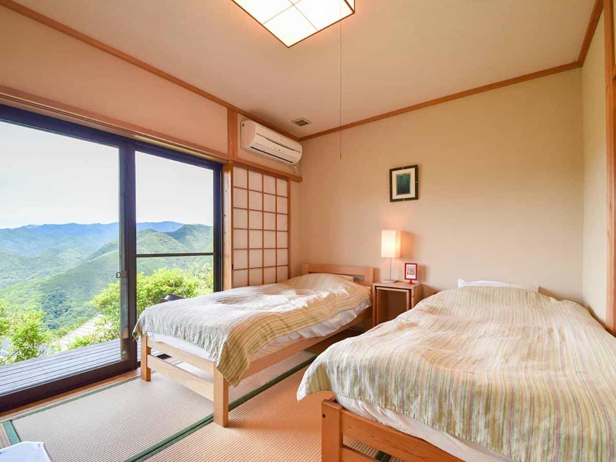 Twin bedroom with tatami mats overlooking lush green mountains from Kirinosato Takahara.