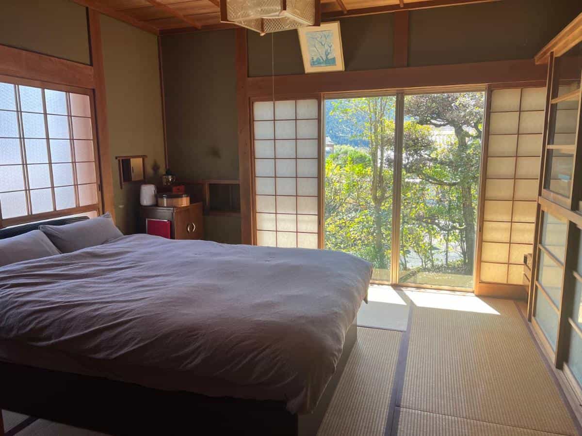 Bedroom with tatami mats, large window, and shoji screens at NONAGASE GUEST HOUSE