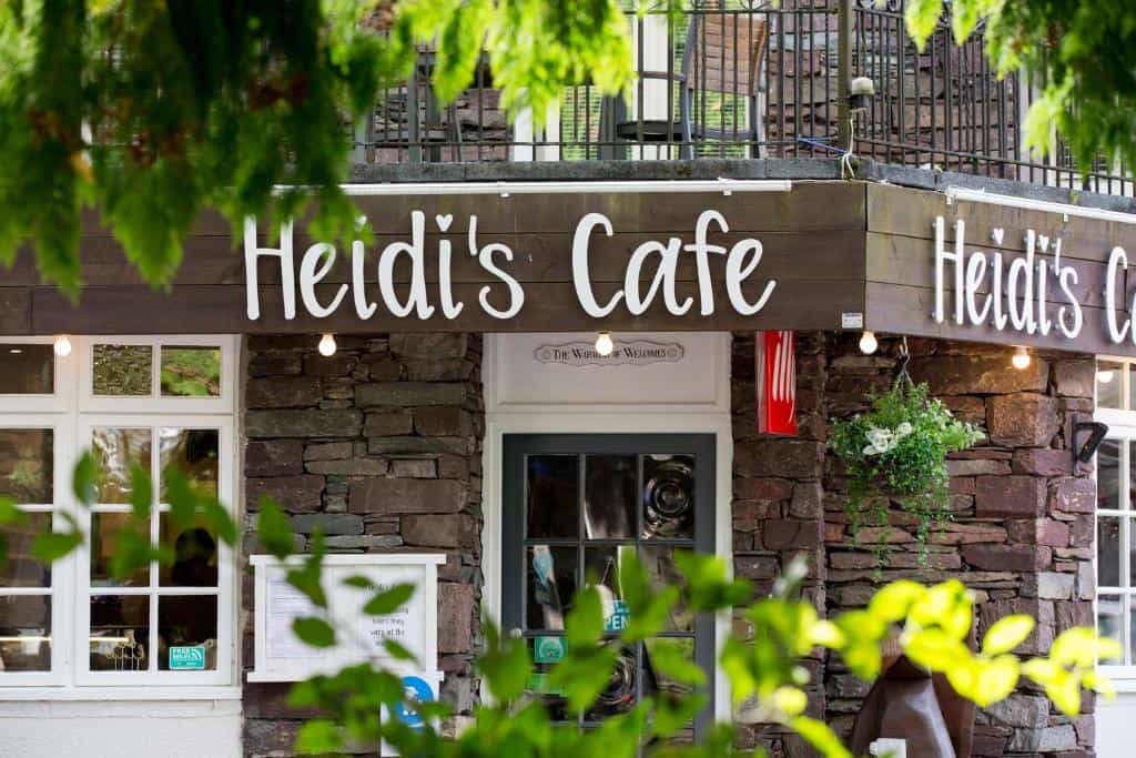 Heidi's Cafe exterior with stone facade, white windows, and green foliage in Grasmere.