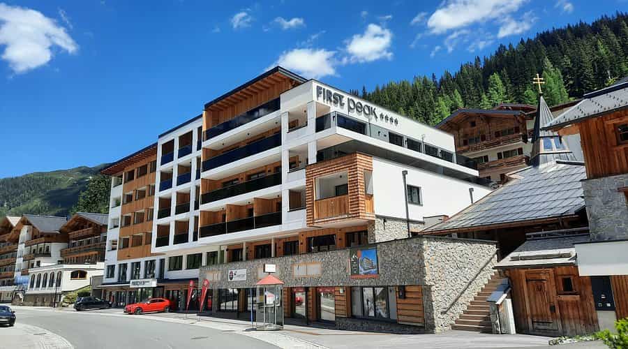 FIRST peak hotel building in Zauchensee with modern wood and stone architecture against forested mountains.
