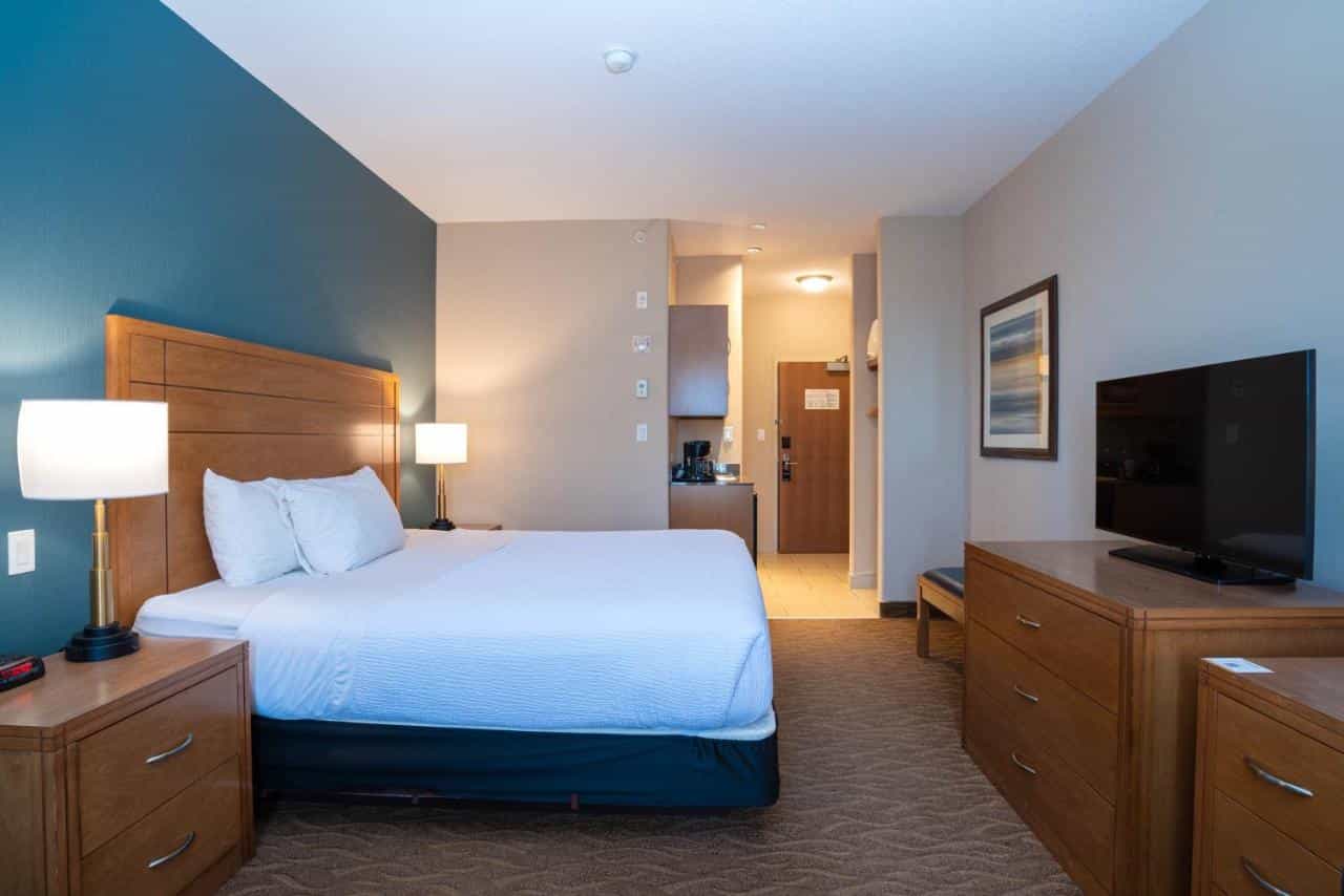 Sandman Hotel room with queen bed, blue accent wall, and wooden furniture.
