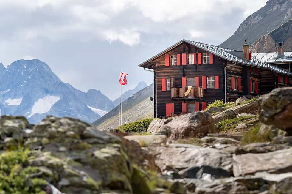 Fluhalp mountain hut with red shutters and Swiss flag in the Swiss Alps.