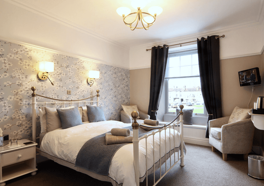 Bedroom in Ivy Cottage Bed & Breakfast with white iron bed and floral wallpaper