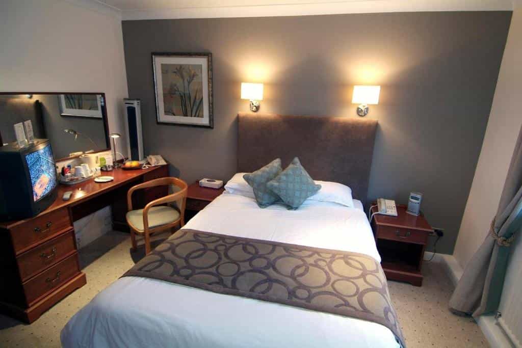 Cozy hotel room with single bed, wooden desk, and CRT television, likely at Wainstones Hotel.
