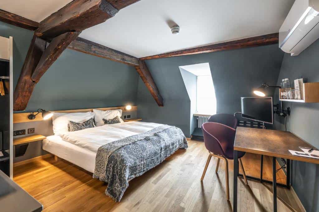 Hotel Jakob attic room with exposed dark wood beams, modern bed, and workspace