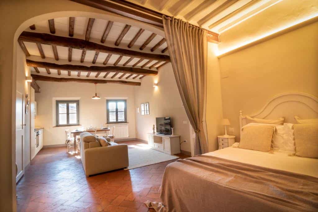 Bedroom and living area with exposed wooden beams and terracotta floors
