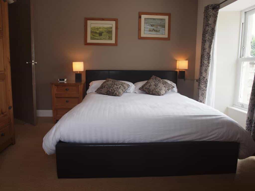 Bedroom with large bed, brown walls, wooden nightstand, and window with patterned curtains.