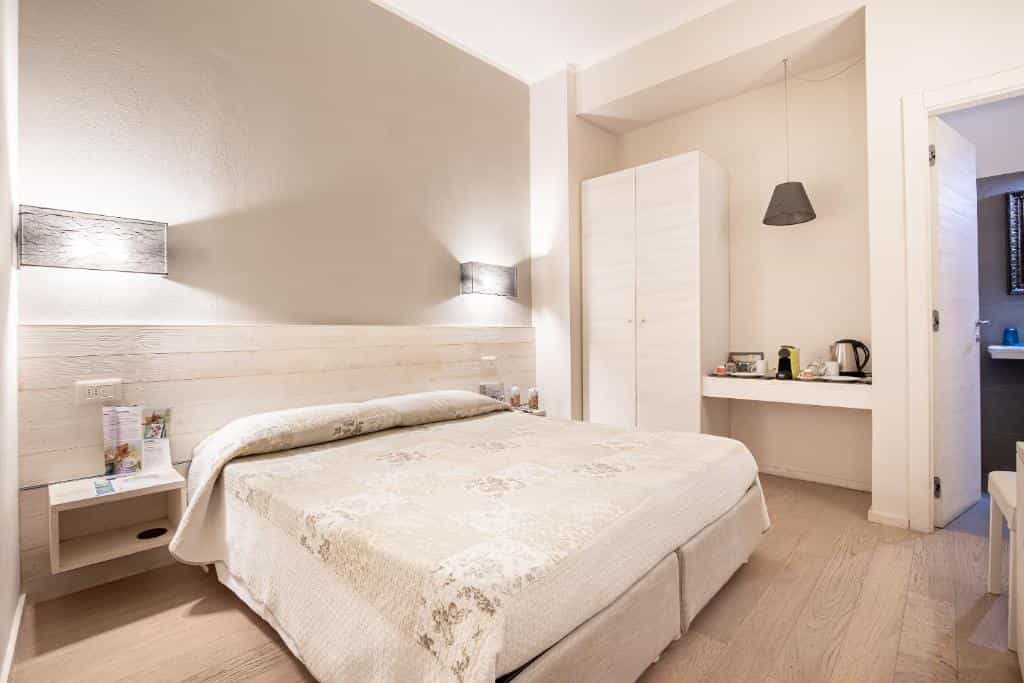 Bright guest room with double bed, white wood paneling, and light wood floor