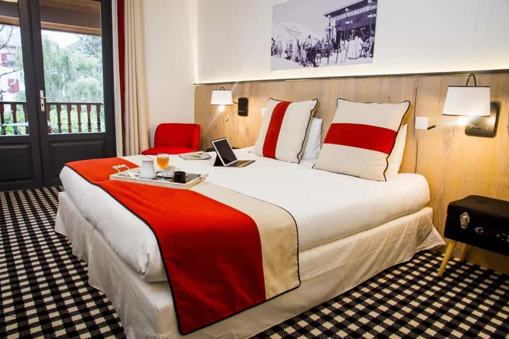Hotel room with large bed, red accents, and balcony access; black and white checkered carpet.