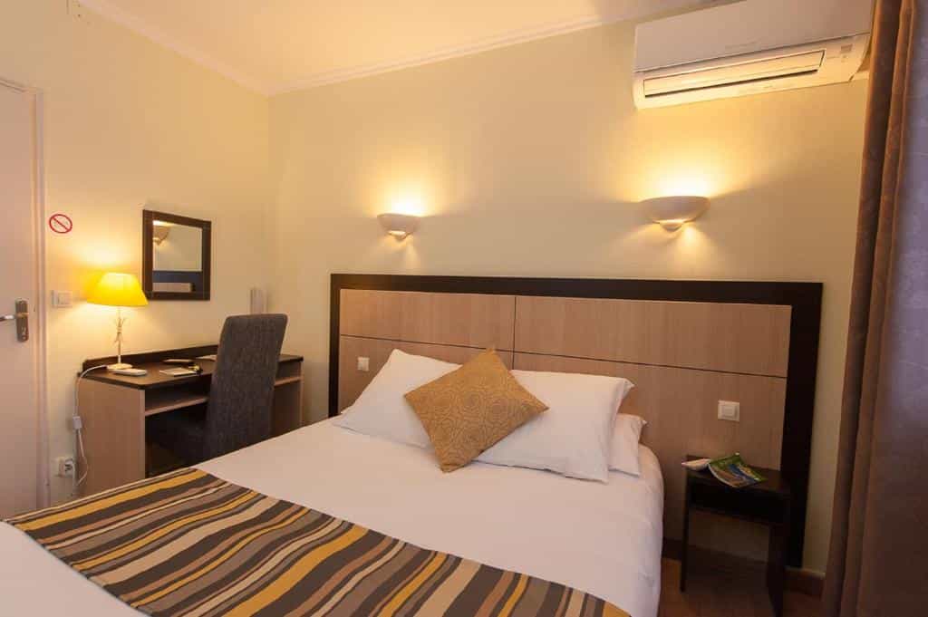 Hotel room with double bed, desk, chair, and wall-mounted air conditioner