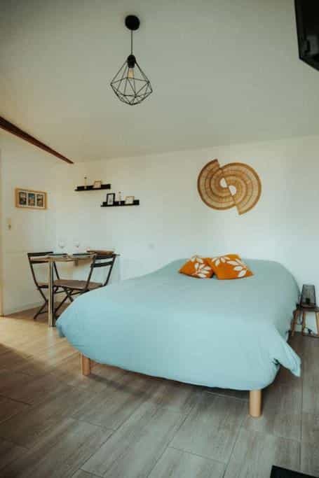 Bedroom with light blue bedding, small dining table, and woven wall art in L'Hospitalet.