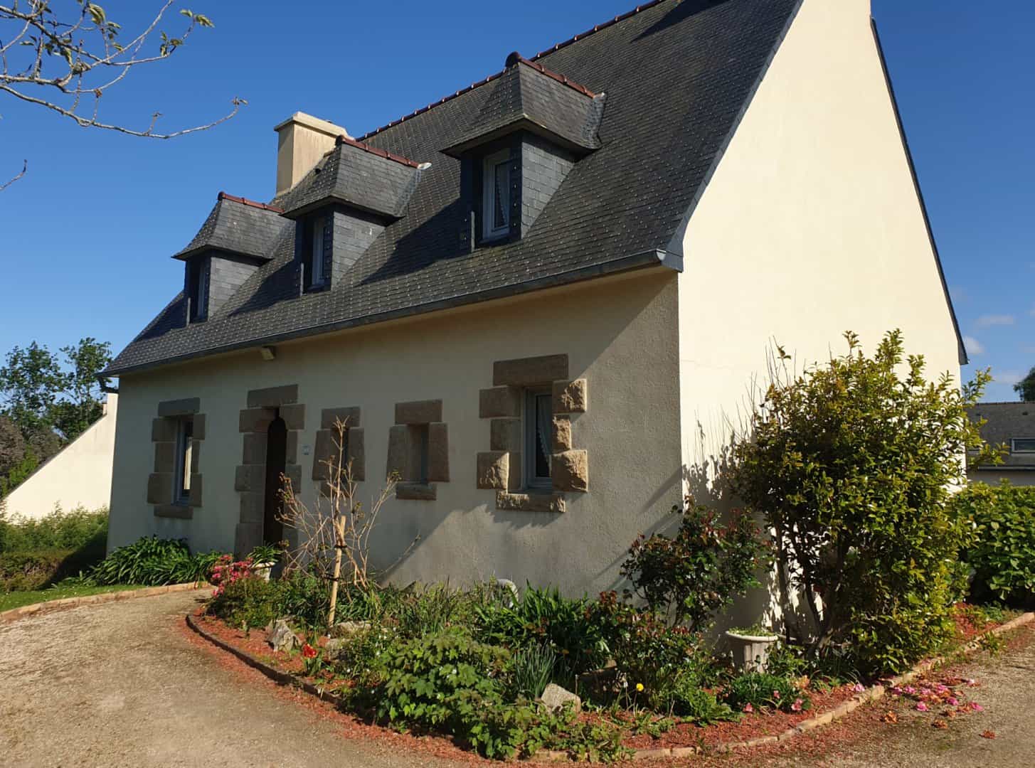 Guesthouse with stone window surrounds and slate roof under blue sky in Trégor area.