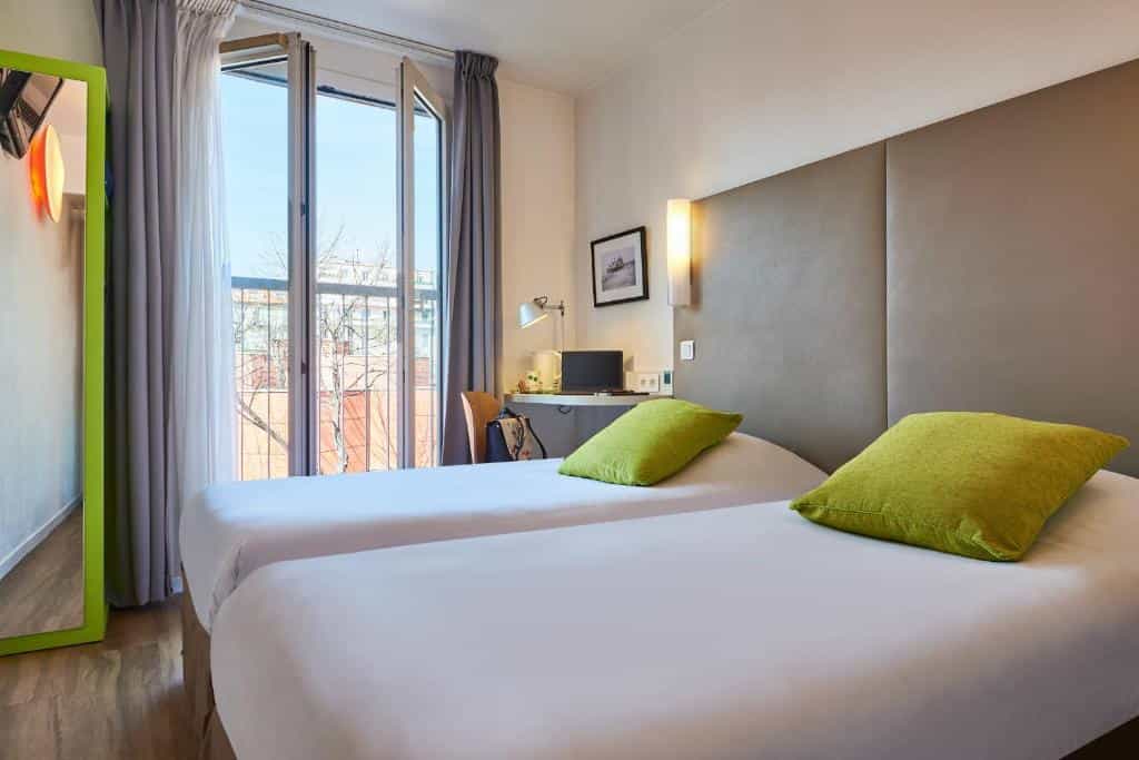 Twin beds with white linens and bright green pillows in a hotel room near Nice Centre Acropolis.