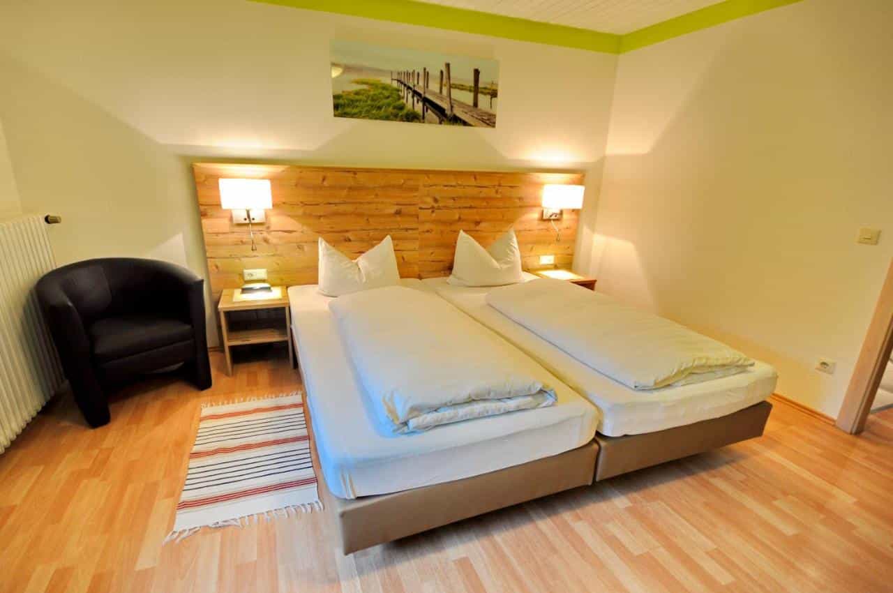 Twin beds with white duvets in a room with wood accents at Wildkräuter-Gasthof Linde.