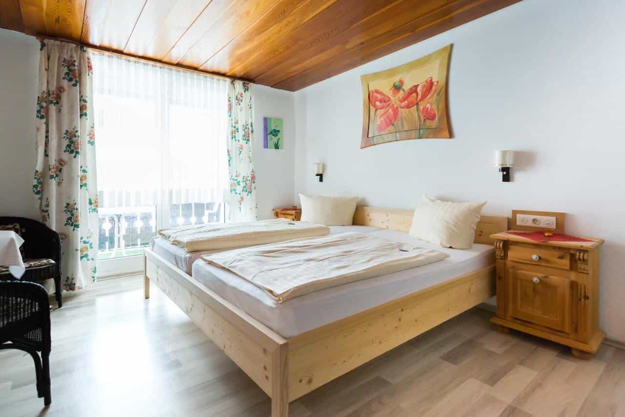 Twin beds with wooden frame, floral curtains, and tulip artwork in a bright hotel room.