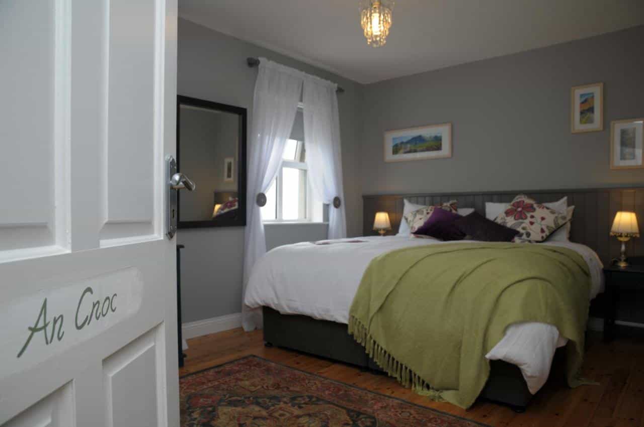 Bedroom with white door labeled "An Cnoc," double bed, and green throw.