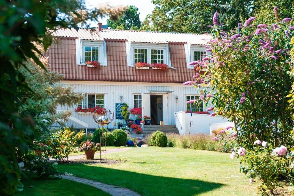 White house with red roof and lush summer garden, Agda Lund Bed & Breakfast