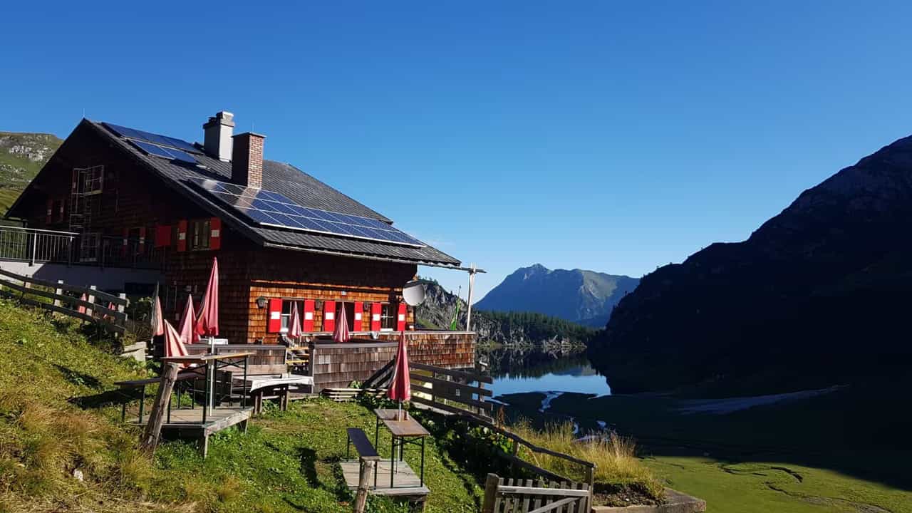Tappenkarseehütte alpine mountain hut with outdoor seating overlooking a lake and mountains.