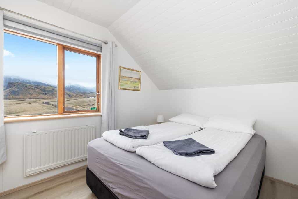 Bedroom with twin beds and mountain view from window at Guesthouse Rauðafell